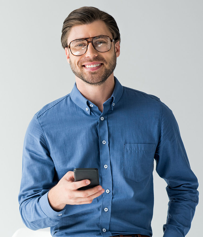 Confident businessman in blue shirt holding a smartphone, representing professional communication or mobile technology.